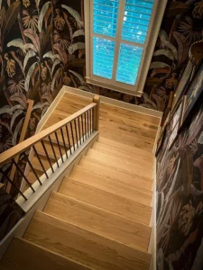 image of an eclectic stairwell with wallpaper and hardwood stairs