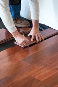 image of man laying down reddish hardwood floor planks
