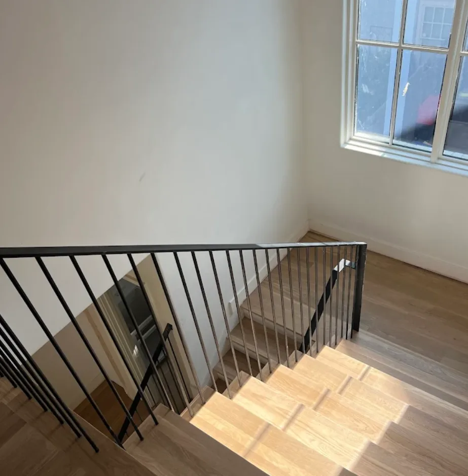 Modern white oak hardwood stair installation with black metal railing in Buckhead, GA